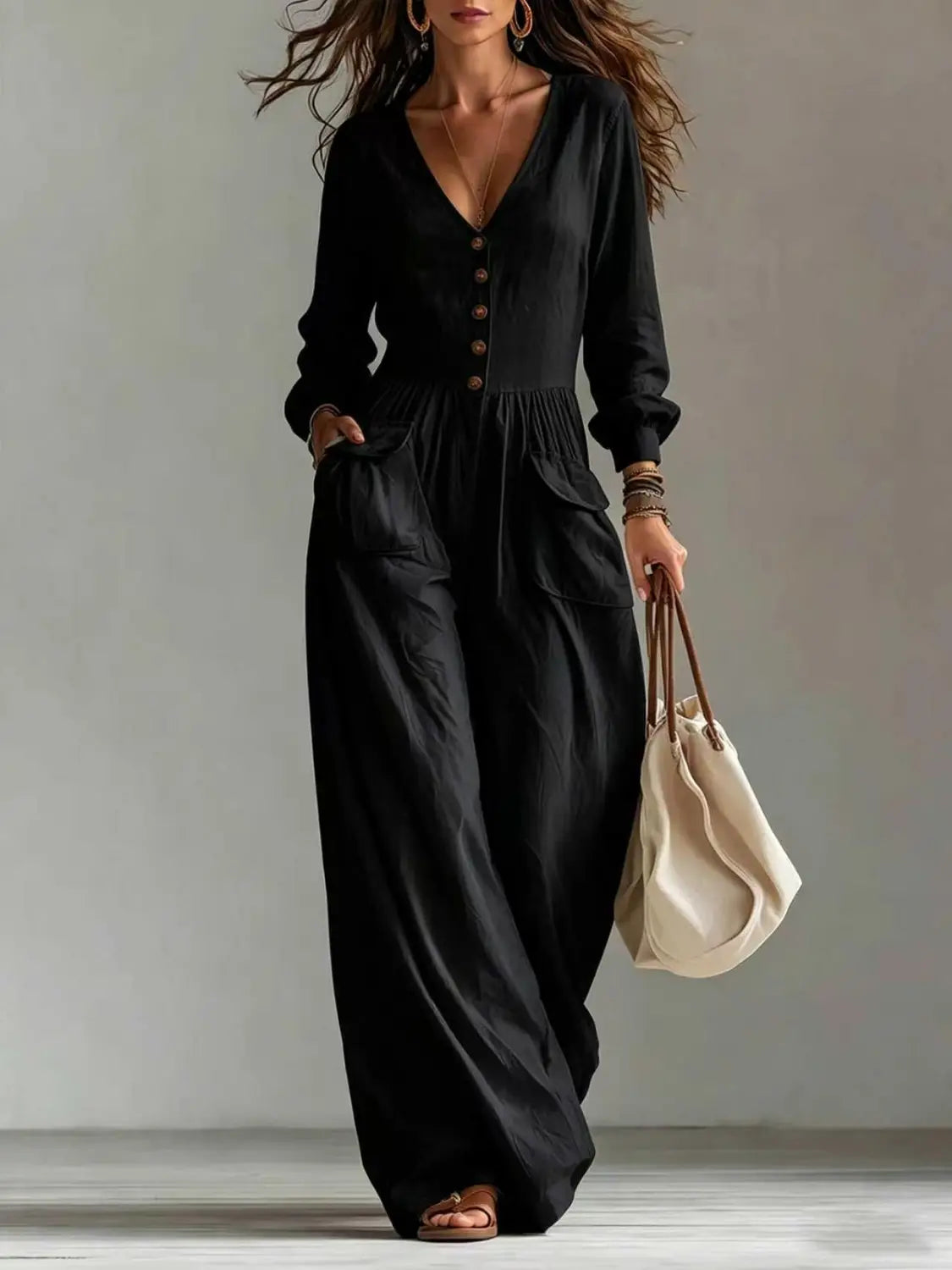 Une combinaison noire à manches longues pour femmes, avec encolure en V, fermeture boutonnée à l’avant et design à jambes larges.