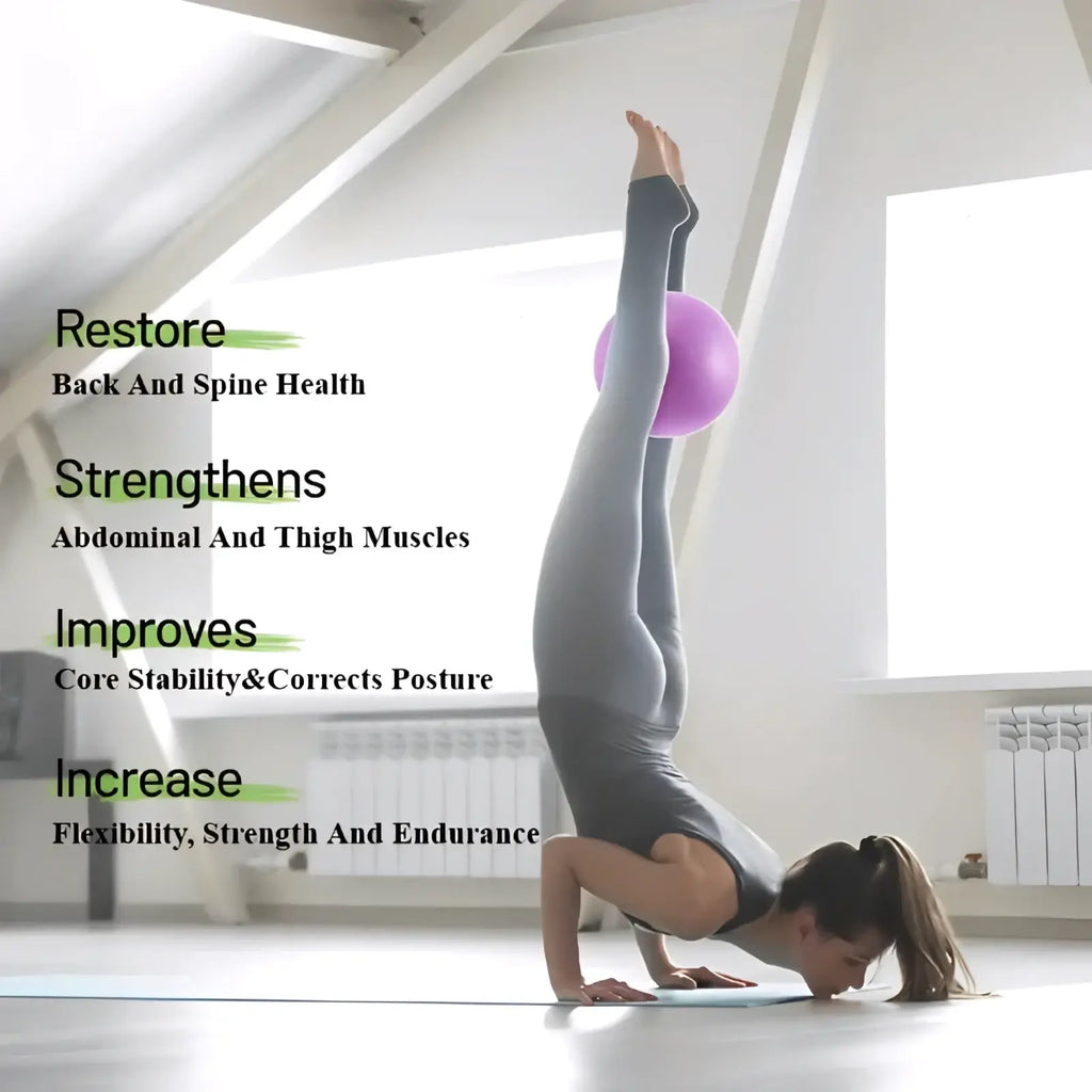 A woman in gray athletic wear performs a handstand balancing on a purple 25cm yoga balance exercise ball