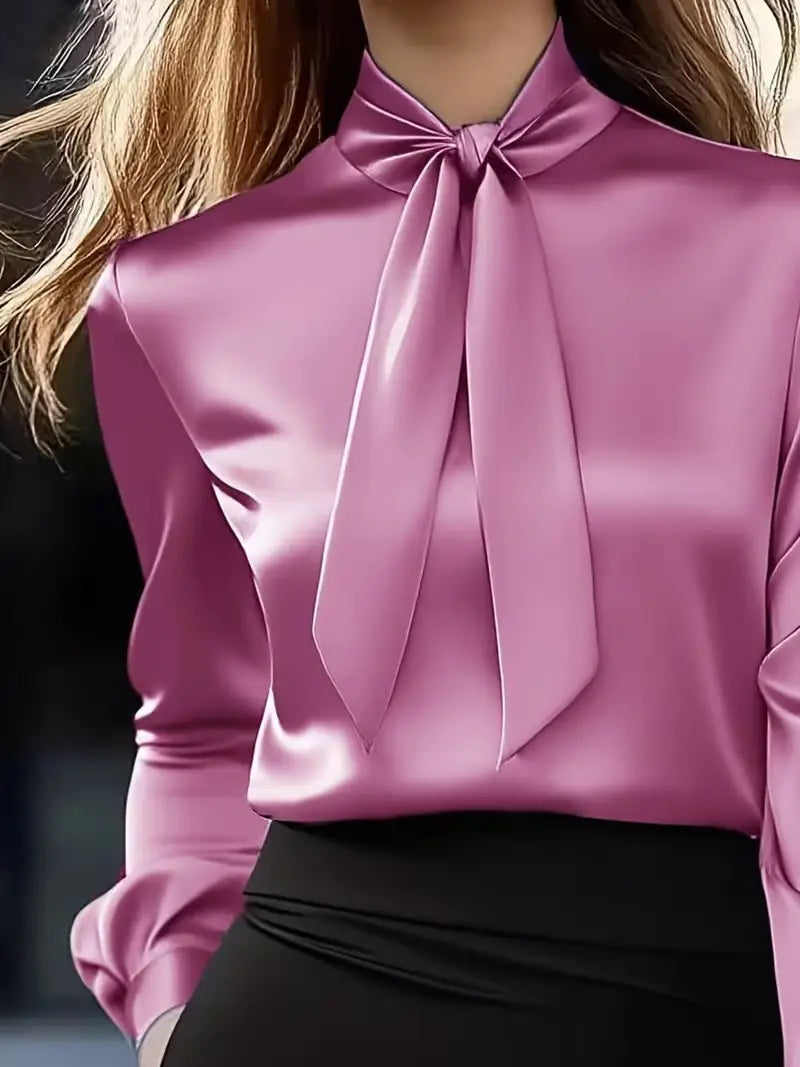 A sleek satin pink blouse with a high neck and an elegant tied bow at the neckline featuring puff sleeves.