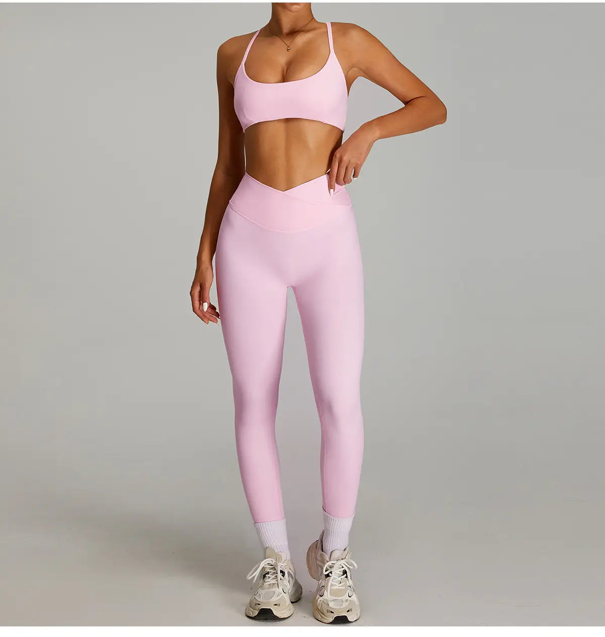 Ensemble deux pièces athlétique rose assorti, avec un haut court offrant un bon maintien et des bretelles fines, ainsi que des leggings de sport taille haute à séchage rapide fabriqués dans un matériau extensible à effet nu.