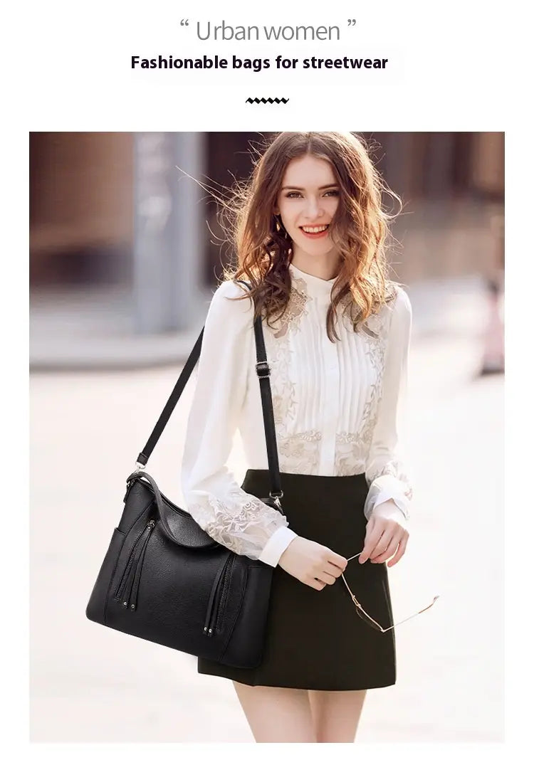 Black leather hobo bag with tassel details and front zipper pockets designed for shoulder carry.