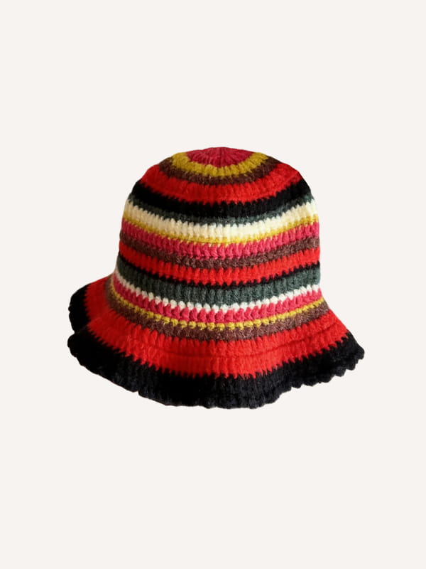 Un chapeau de pêcheur multicolore tricoté à la main, éclatant, avec des rayures horizontales audacieuses rouge, noir, jaune, crème et vert, muni d’un bord à volants.