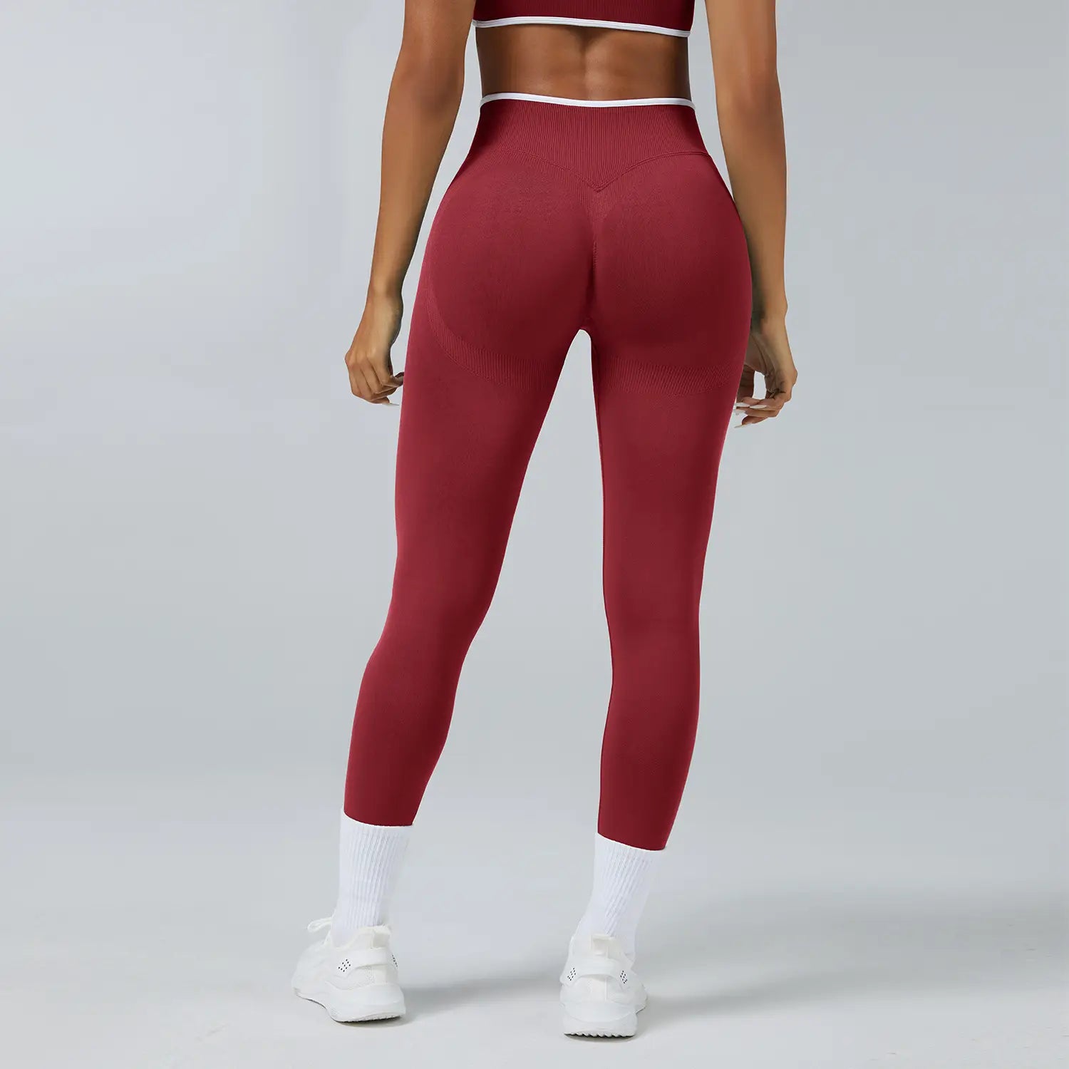 Nahtlose Sport-Yoga-Leggings mit hoher Taille in Bordeauxrot mit gerippter Struktur und weißem Zierbesatz am Bund.