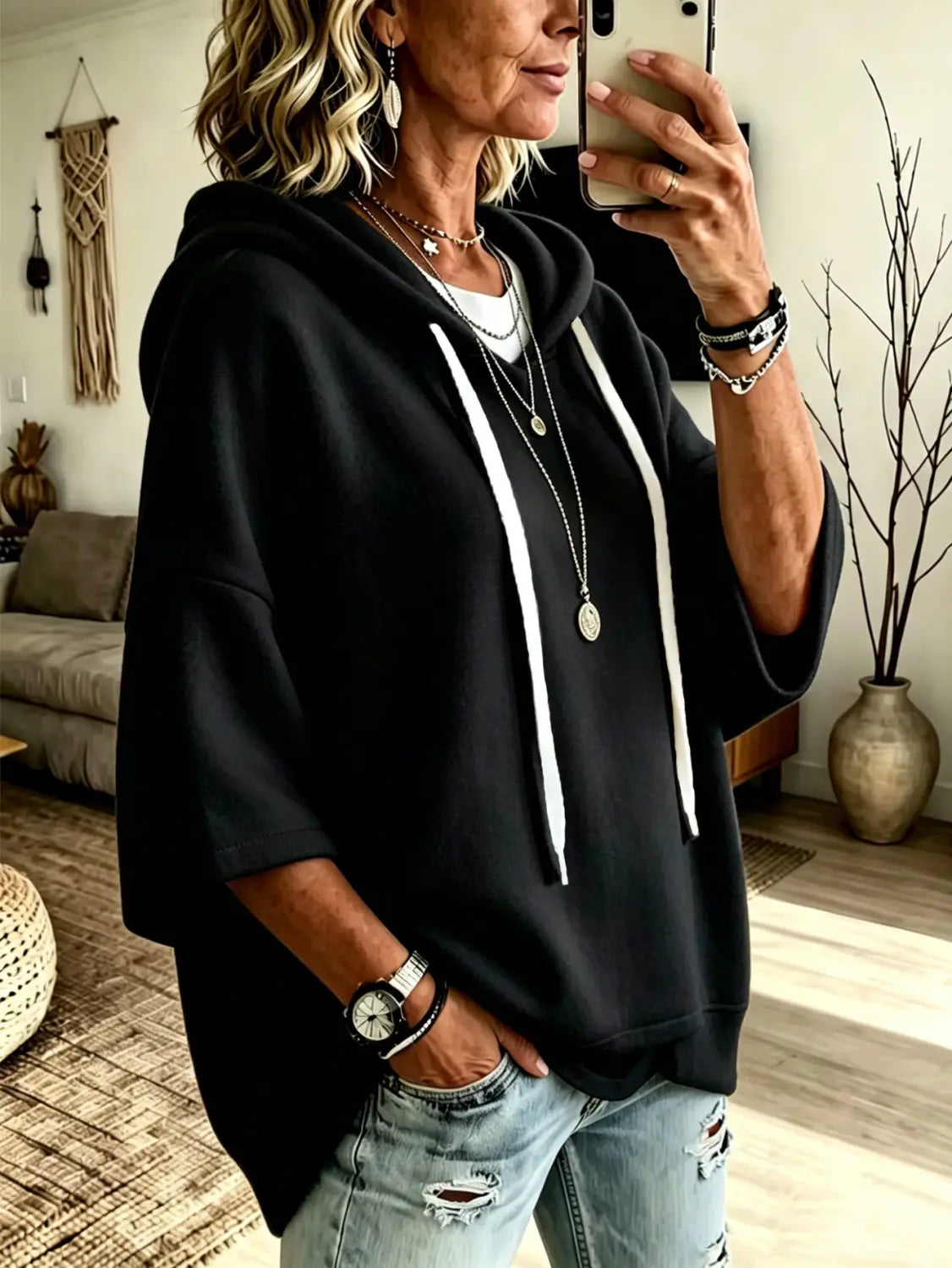 black oversized fleece hooded top with three-quarter sleeves and white drawstrings displayed from the front