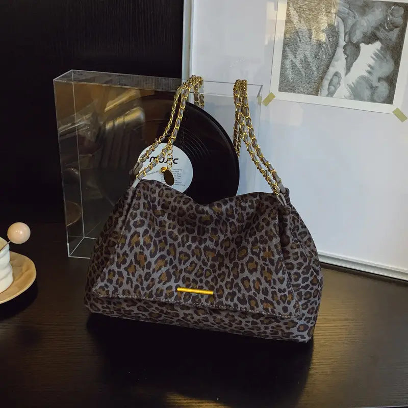 Leopard print crossbody bag with gold-tone chain strap and matching metallic clasp.
