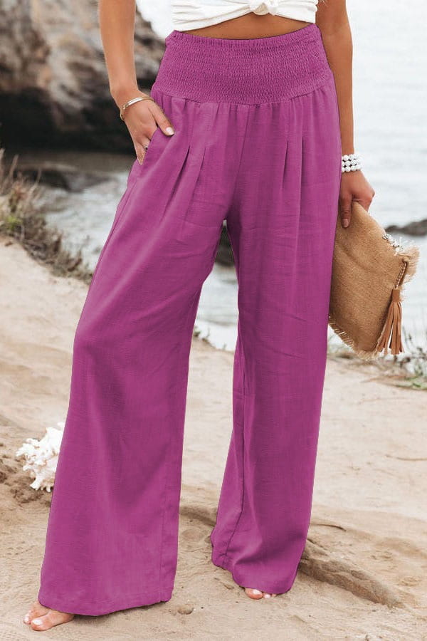 Purple high-waisted wide-leg pants for women with a smocked elastic waistband and flowing fabric in solid color.