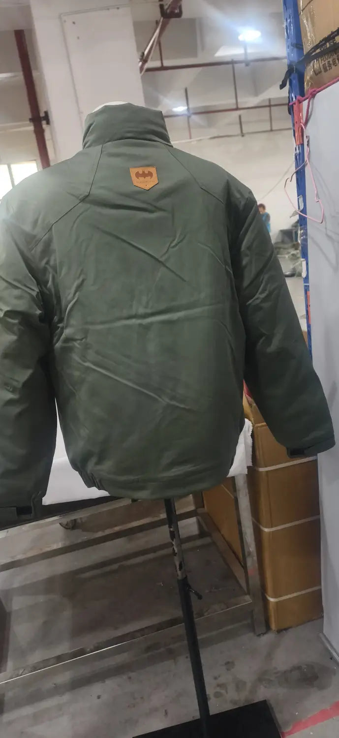 Herren-Steppjacke für Arbeitskleidung in Olivgrün im Puffer-Stil mit Steppdesign und einem kleinen orangefarbenen Patch auf der Rückseite.