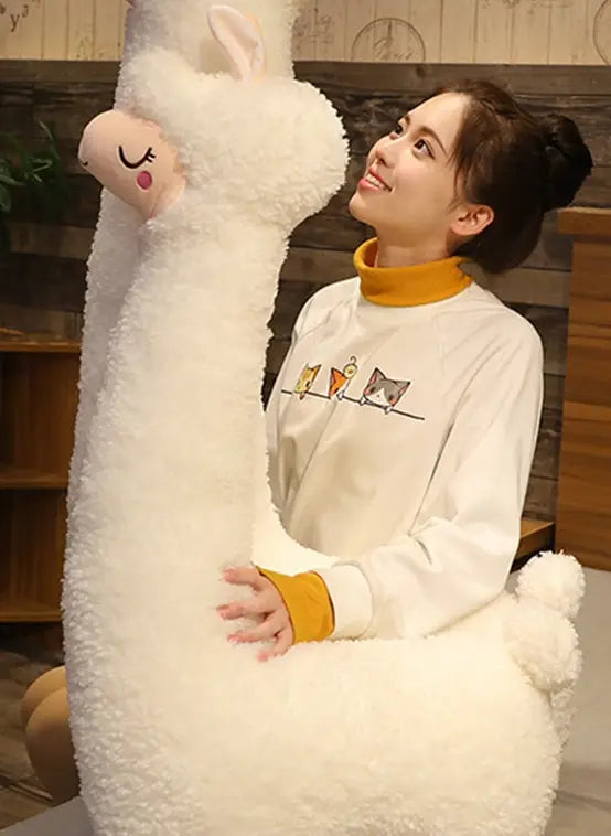 A plush white alpaca stuffed animal pillow measuring 75cm with soft fluffy fur and a cute face featuring closed eyes and pink cheeks.