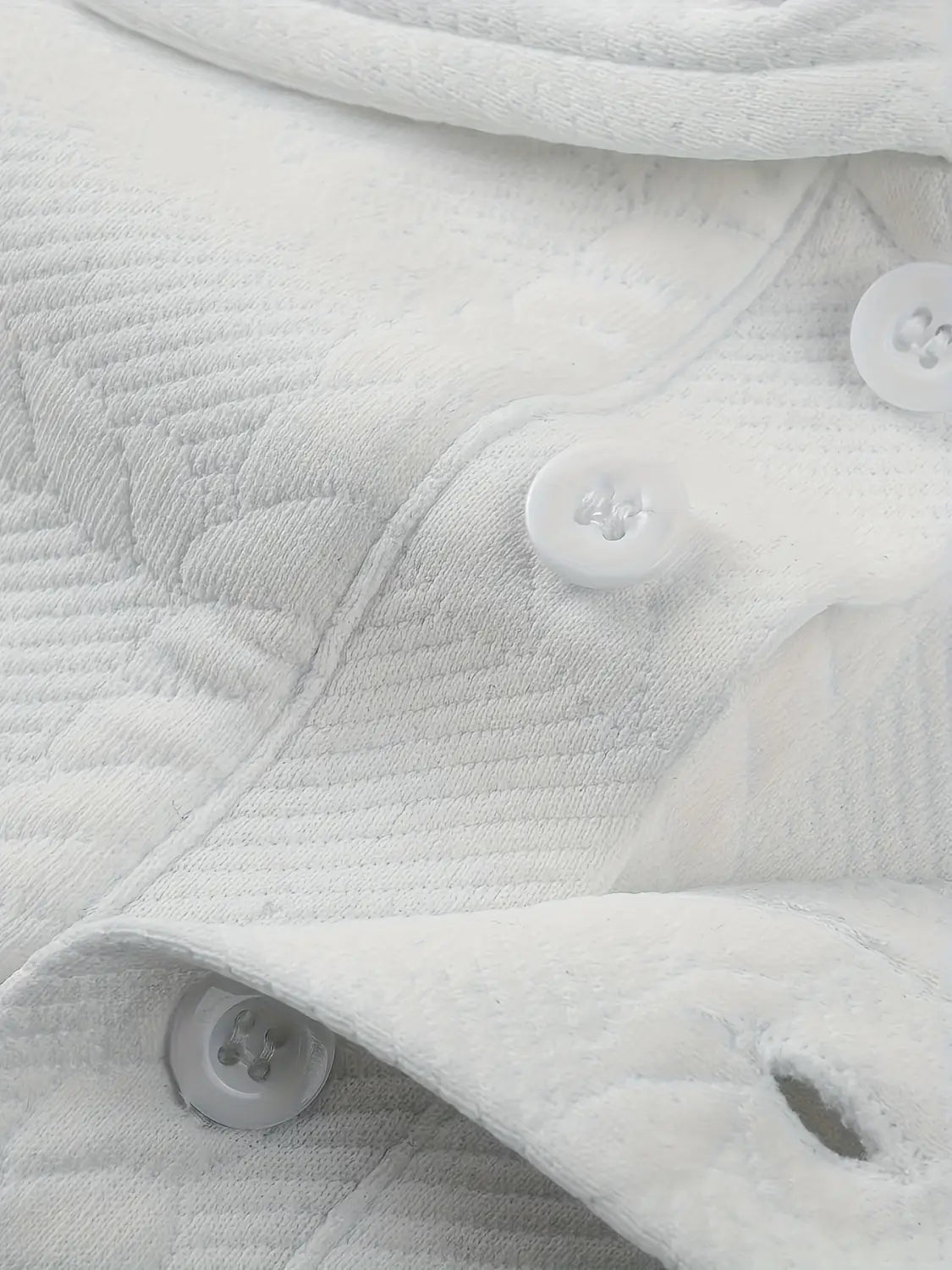 Tela acolchada blanca para camisa tipo polo de manga larga con textura, con botones blancos a juego.