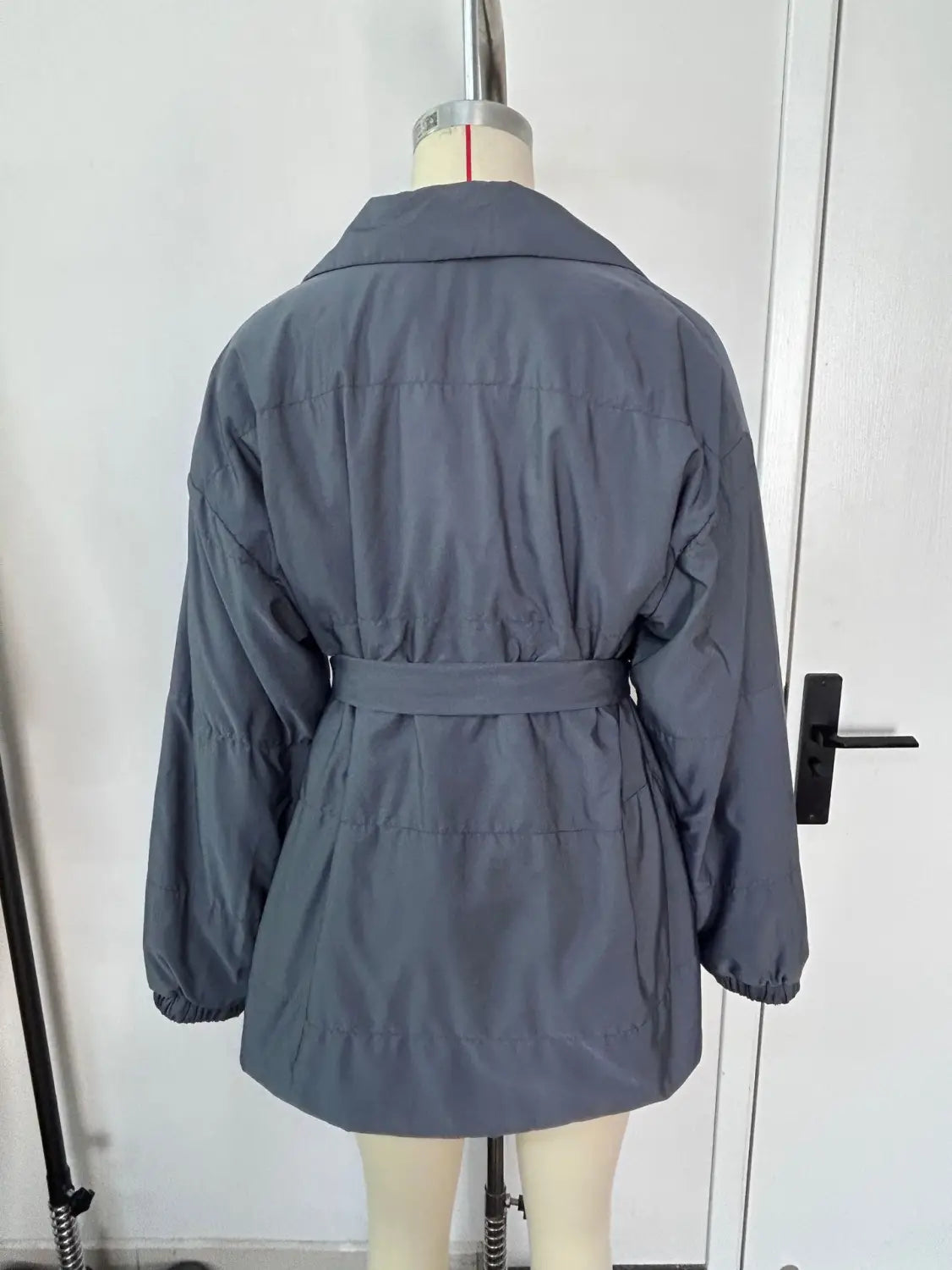 Damen-Gurtsteppjacke mit Kapuze, wattierte Pufferjacke für den Winter in Grau, mit Taillengürtel und langen Ärmeln, für kaltes Wetter entworfen.