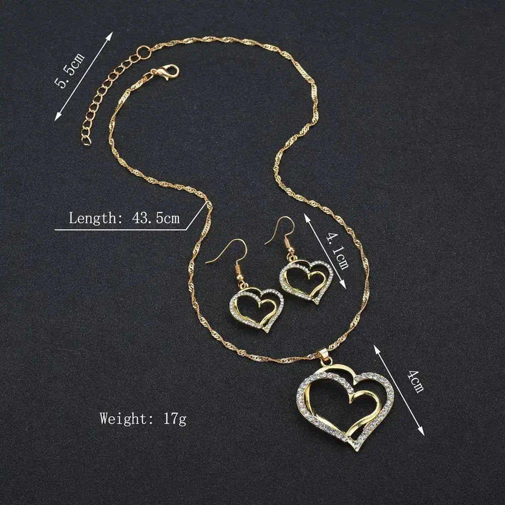 Elegant rhinestone heart jewelry set featuring a gold-toned chain necklace with an open-heart pendant adorned with clear rhinestones and matching drop earrings with a delicate twisted link design.