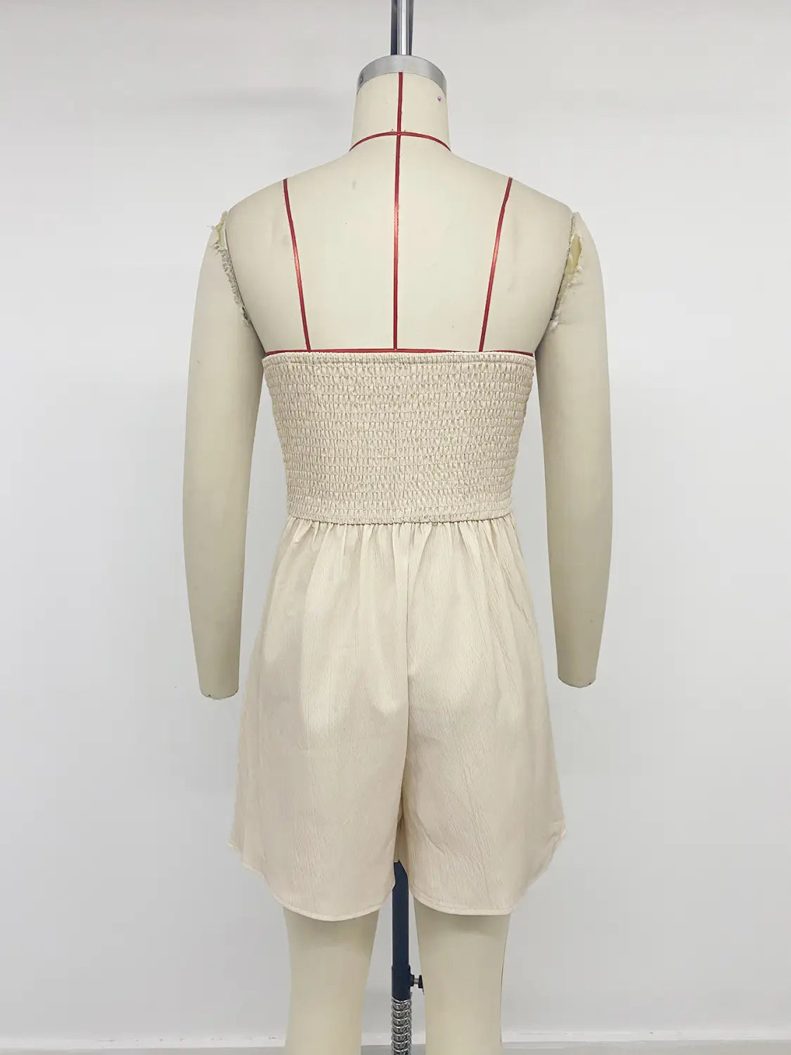 beige smocked bodice romper with gathered waist and long sleeves shown as an alternative to the cream strapless pleated jumpsuit.