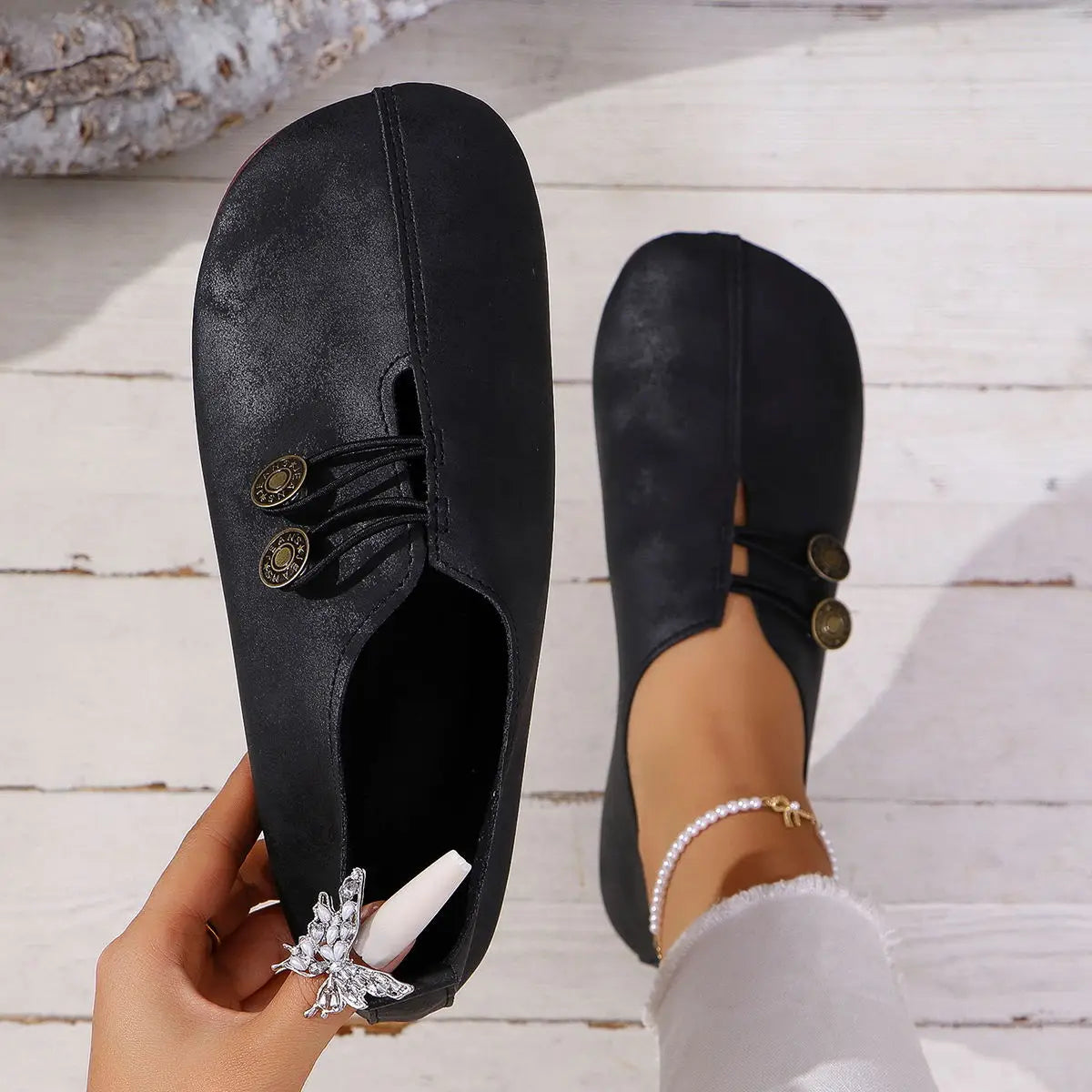 Black suede flat loafers for women featuring square toes, lace-up leather detailing, gold-tone buttons, and a silver butterfly charm.