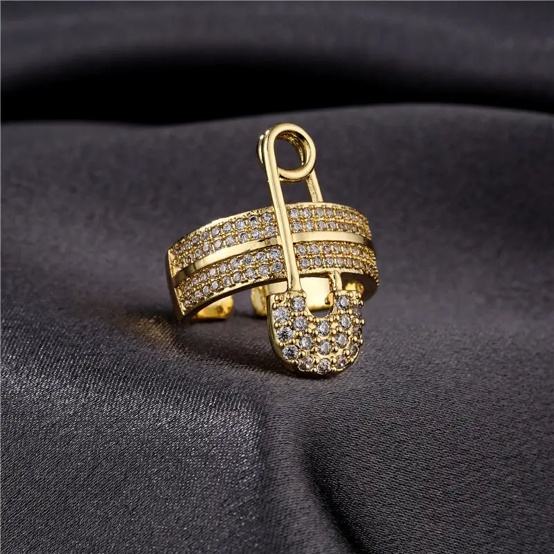 Adjustable gold safety pin zircon geometric ring featuring a gold-toned band embellished with sparkling clear crystals along its band and clasp.