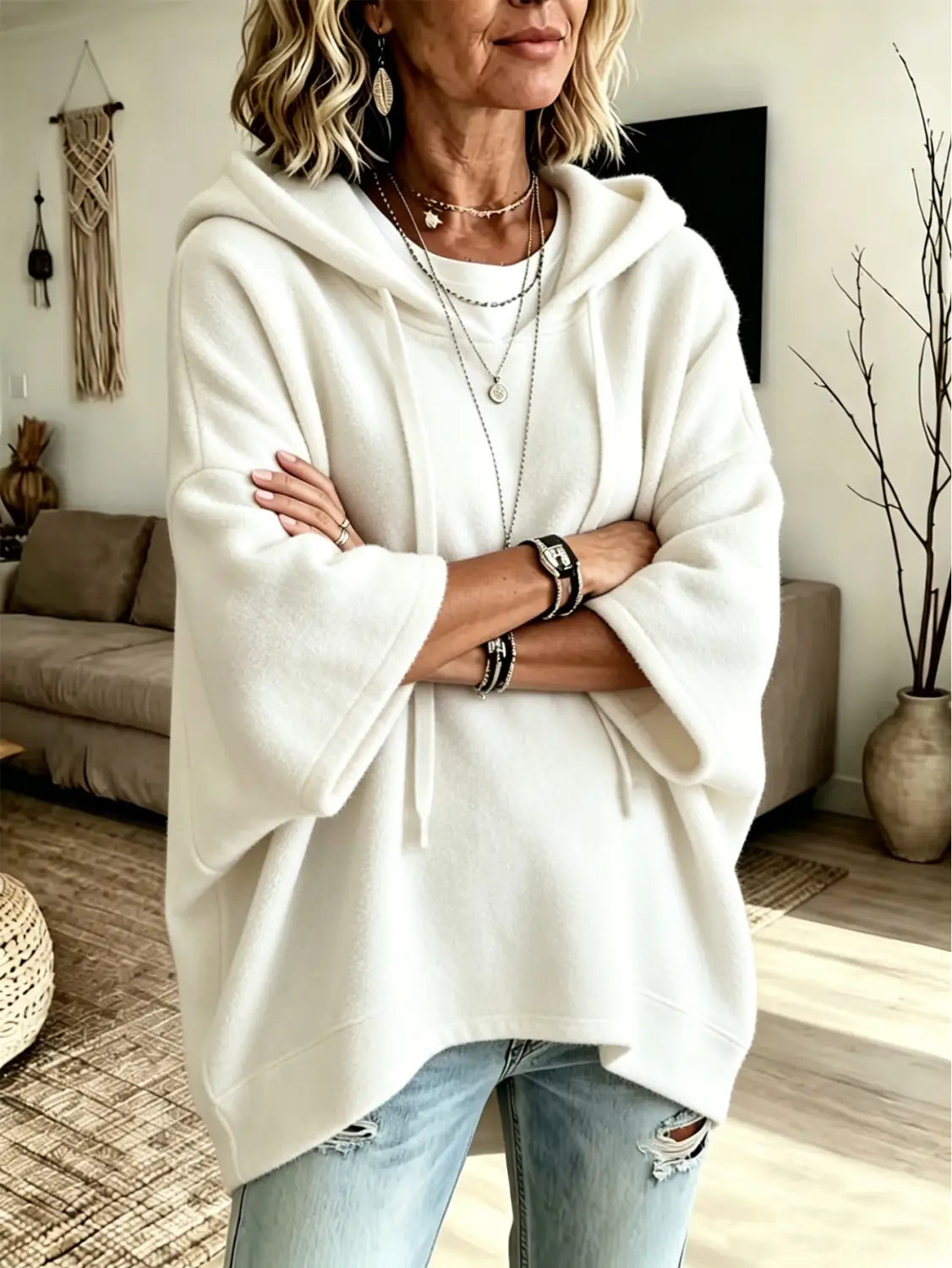 A soft off-white oversized fleece hooded top with three-quarter sleeves featuring a relaxed fit and drawstring hood.