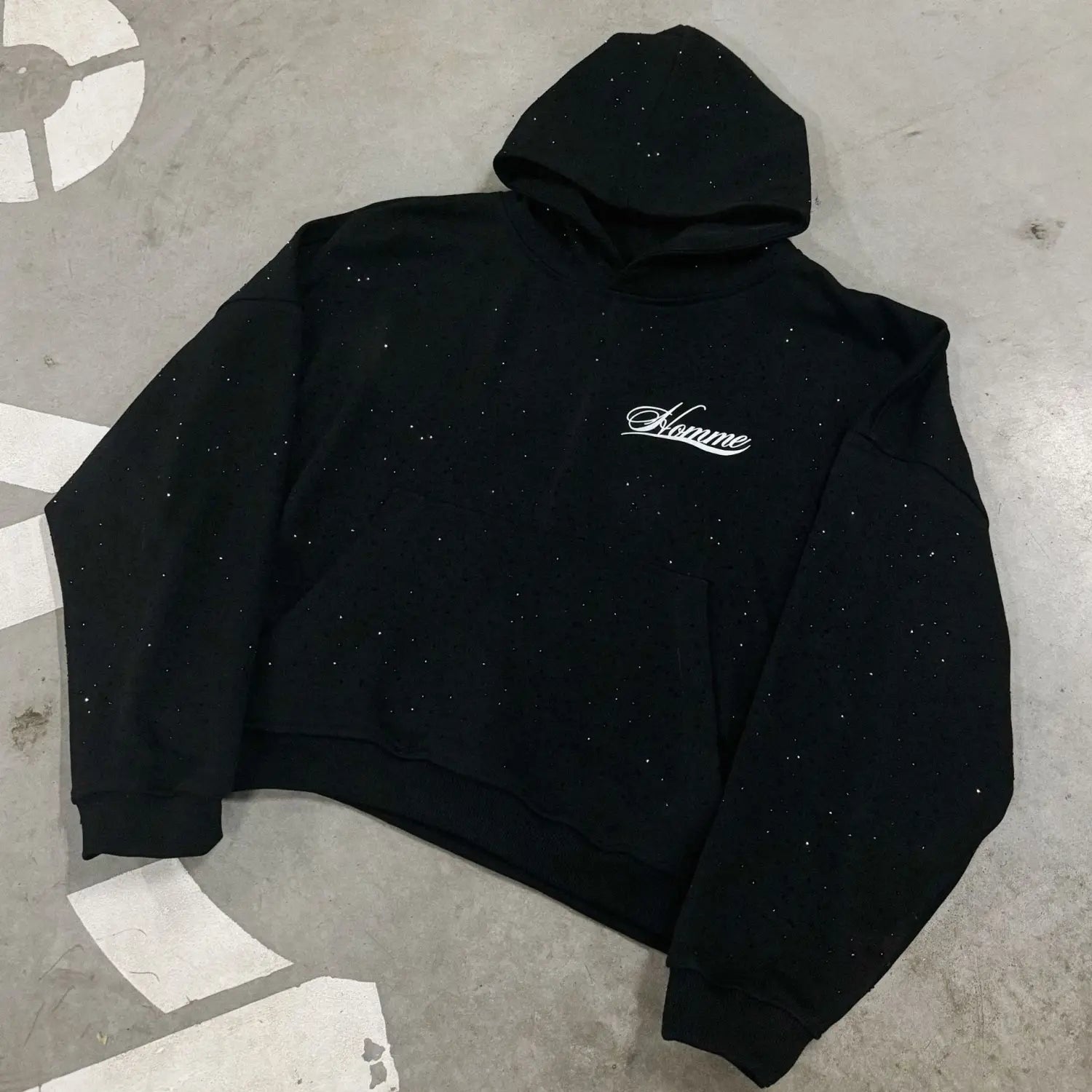 Sudadera negra del Proyecto Starry Streetwear, con una textura sutil con brillo y bordado blanco en cursiva de estilo homme en el pecho, en un diseño de moda de ajuste holgado.