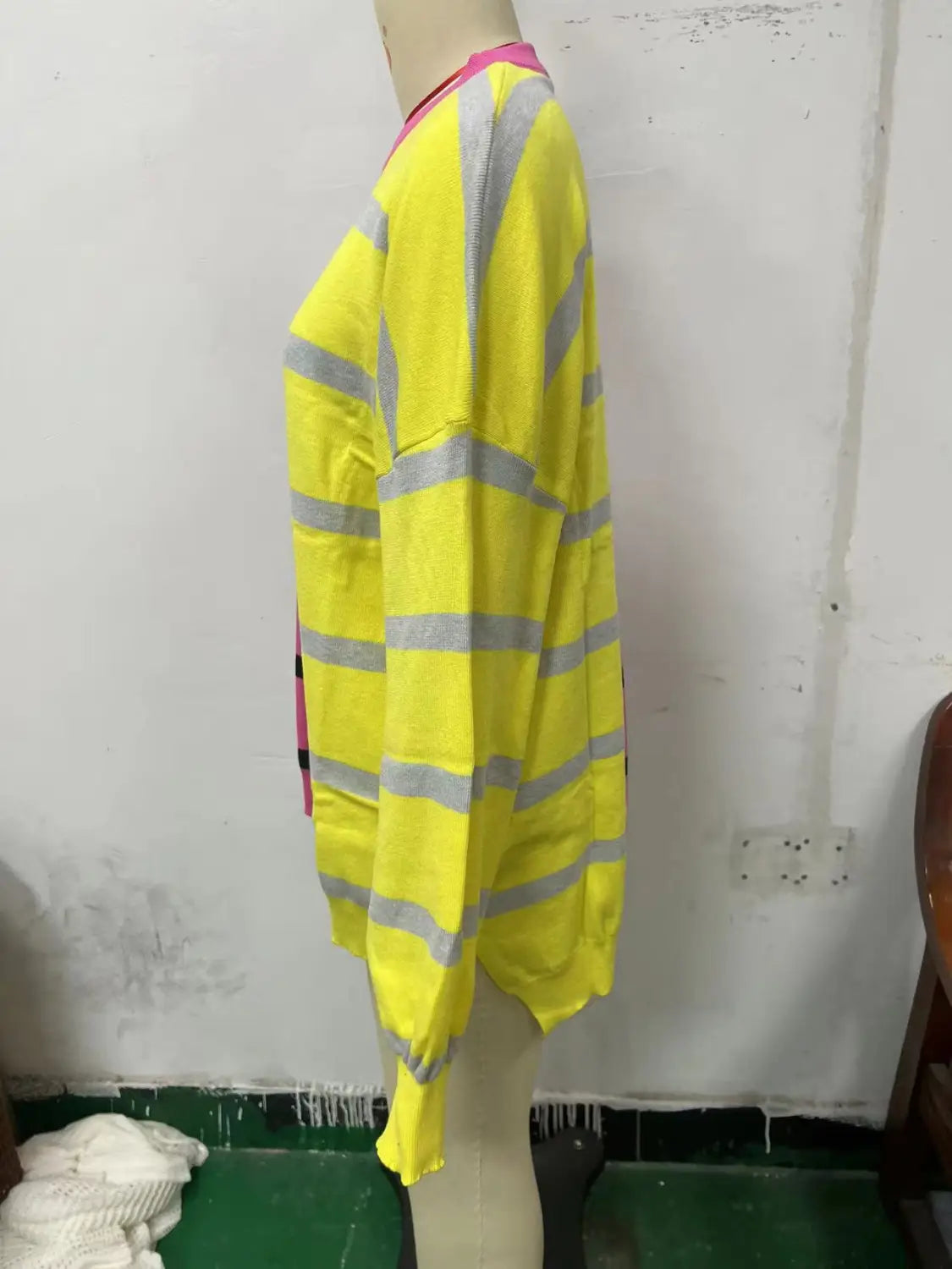 Women’s oversized split color striped knit sweater featuring a bright yellow long-sleeved design with gray horizontal stripes and a pink collar.