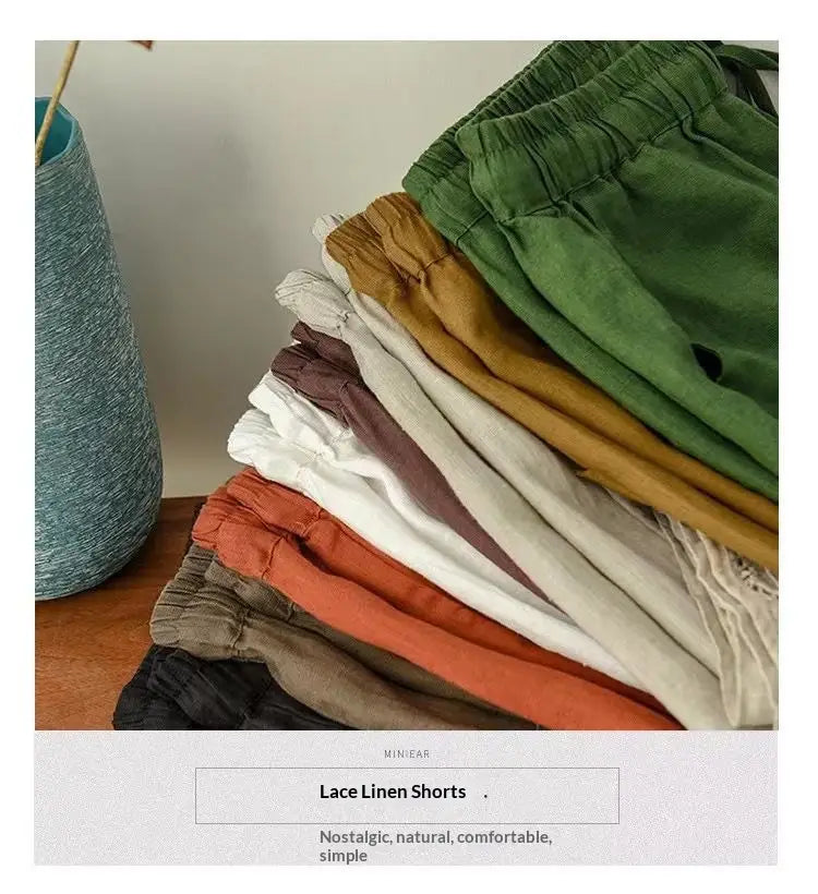 eine Stapel aus weichen Baumwoll-Leinen-Hosen mit geradem Bein und Schnürung in erdigen, gedämpften Grün-, Orange- und Neutraltonen.