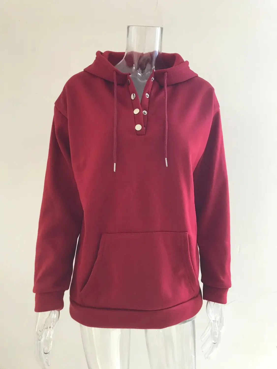 A maroon women’s hooded sweatshirt with a button neck placket and white drawstrings made from soft fabric.