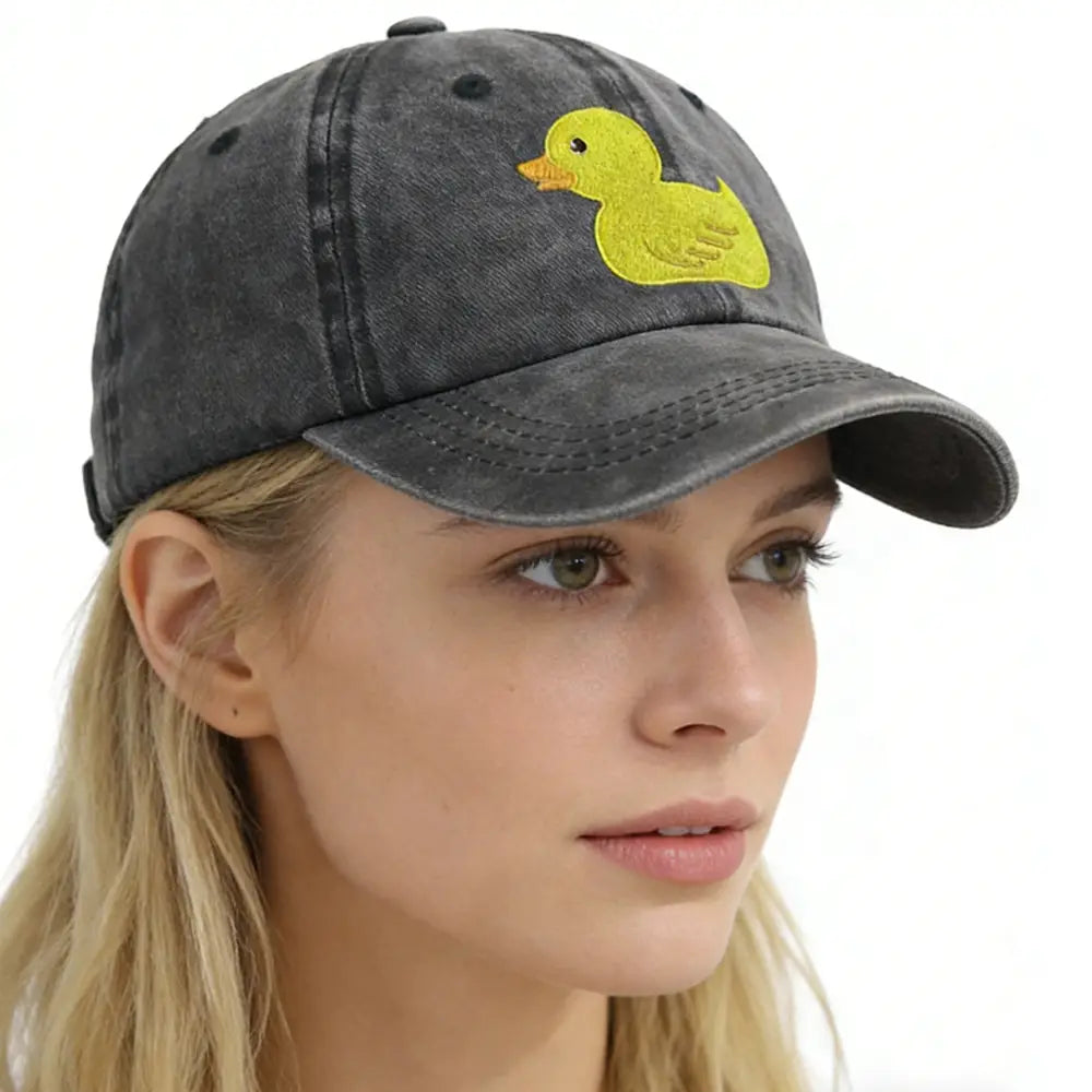 A dark gray distressed denim baseball cap featuring a bright yellow embroidered duck with an orange beak.