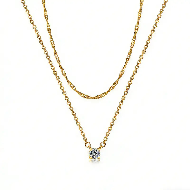 14k gold plated dainty diamond solitaire pendant necklace featuring a gold-toned double-layer chain with one twisted strand and one smooth strand, adorned with a single round-cut clear gemstone in a four-prong setting.