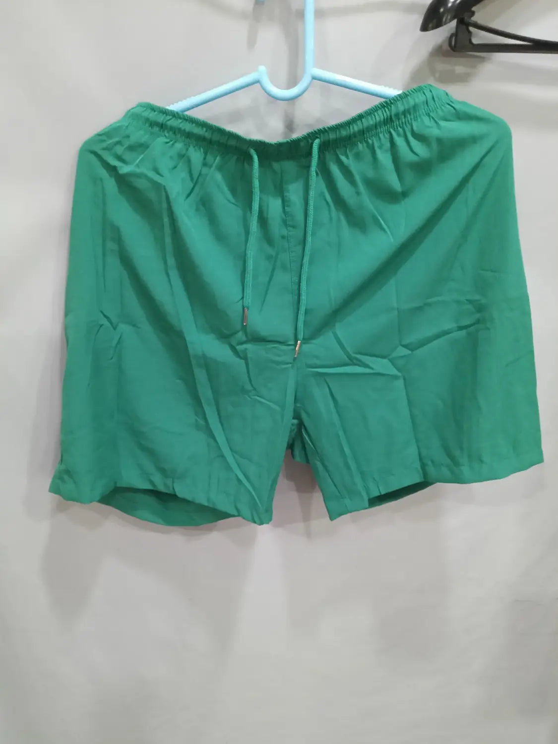 Green printed men beach shorts made of lightweight material feature an elastic waistband with a matching drawstring designed for summer swim trunks.
