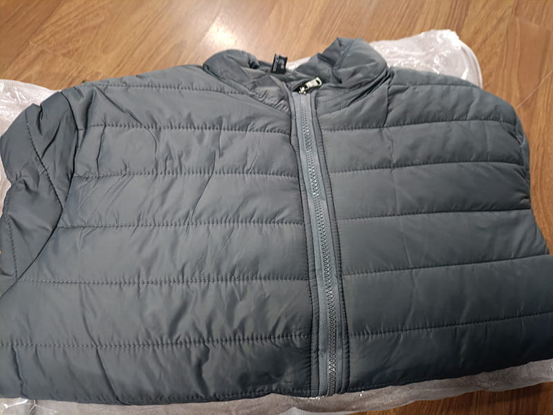Doudoune matelassée grise pour homme avec col montant, capuche, fermeture centrale à glissière et matière isolante pour la saison froide.