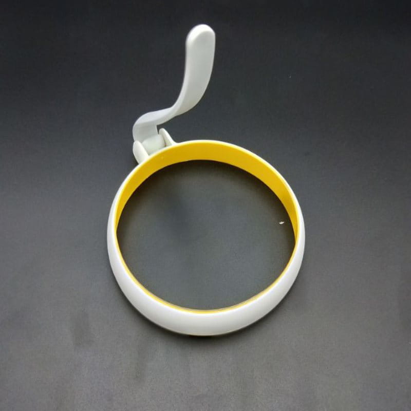 Eierring aus Silikon in Weiß und Gelb für eine runde Omelettform mit gebogenem Griff zum mühelosen Wenden