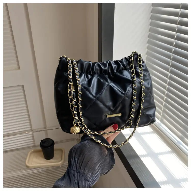 Black quilted faux leather crossbody bag with satin finish gold-tone chain straps and decorative golden ball charm.
