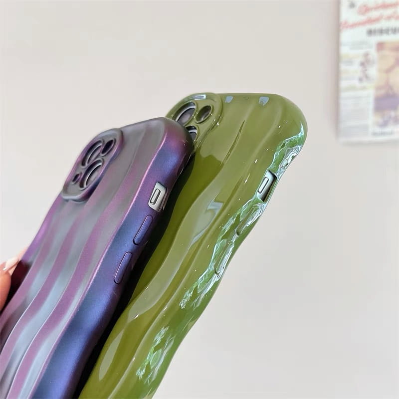 Two glossy wavy liquid silicone iPhone cases shown from the back side featuring a purple and blue striped gradient and a solid olive green color.
