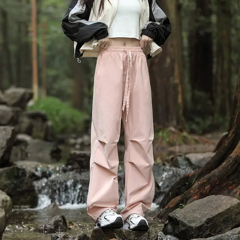 pleated cargo hiking pants for men and women in soft pink slightly shiny fabric with an elastic waistband and drawstring.
