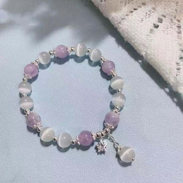 A crystal butterfly cat’s eye bead bracelet featuring alternating lavender and white beads with silver-toned metal spacers and a dangling star charm.