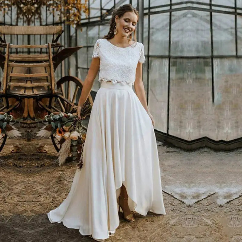 Robe de mariée en dentelle blanche et satin à manches courtes, décolleté bijou, avec ourlet hauteur-faible en blanc.