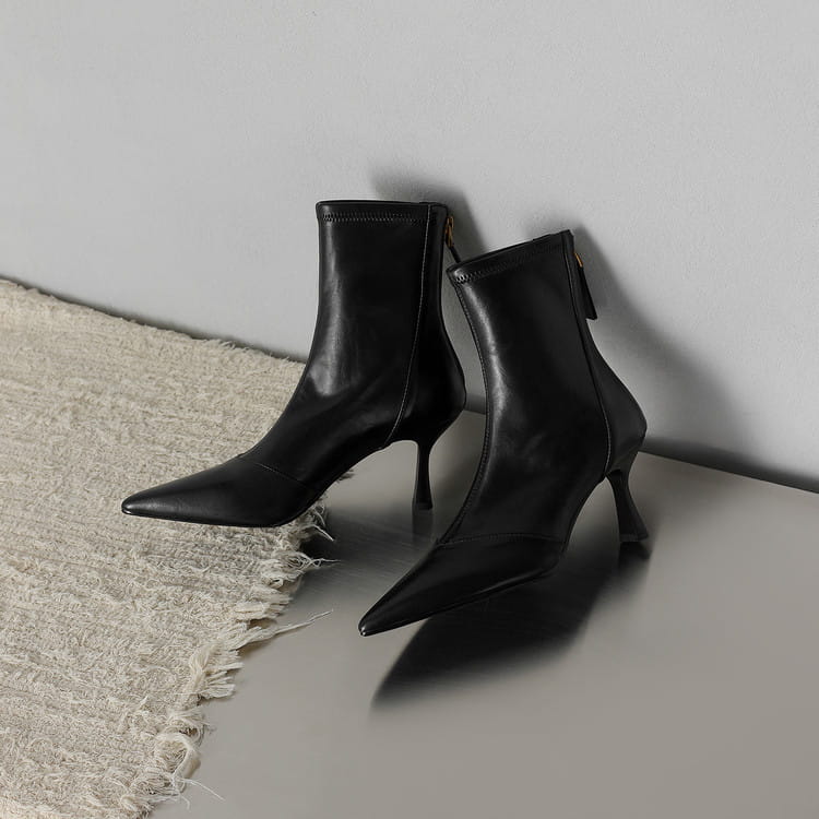 Black leather pointed toe cowhide stiletto ankle boots with zipper and slender high heel shown from the back side.