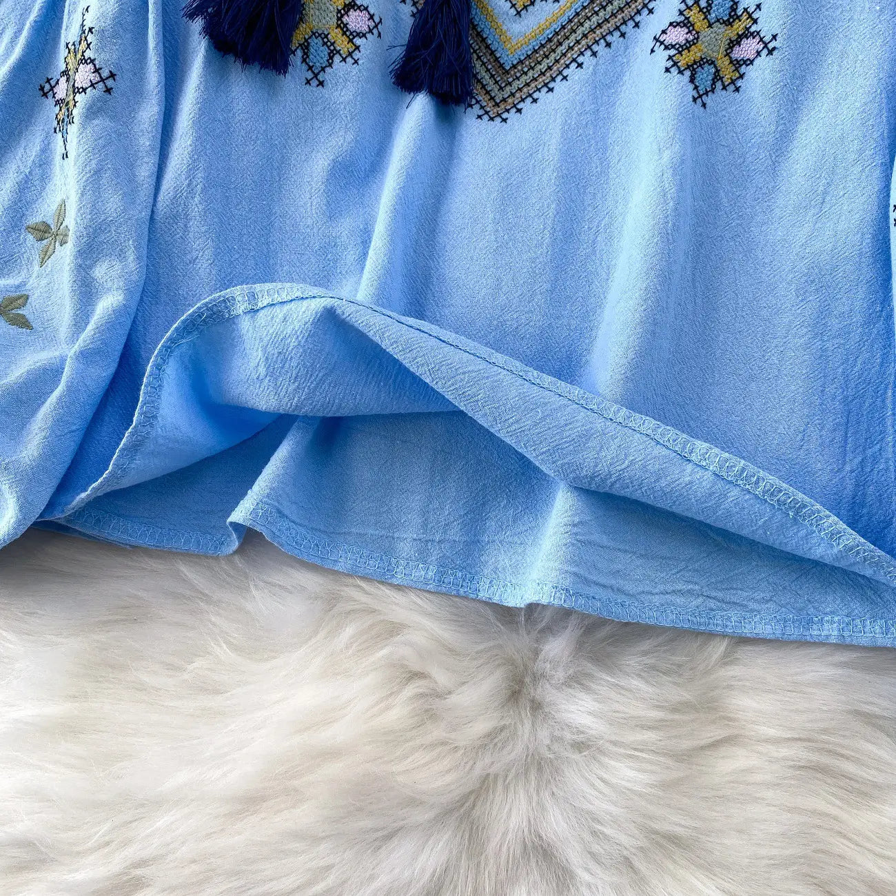 Light blue embroidered lantern sleeve tie neck blouse with intricate geometric patterns and dark tassels.