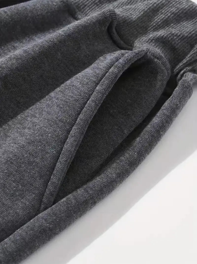 Dunkelgraue Herren-Frottee-Jogginghose mit geripptem Strick, weiche strukturierte Stoffqualität und elastischem Bund, ideal für den Casual-Streetwear-Stil.