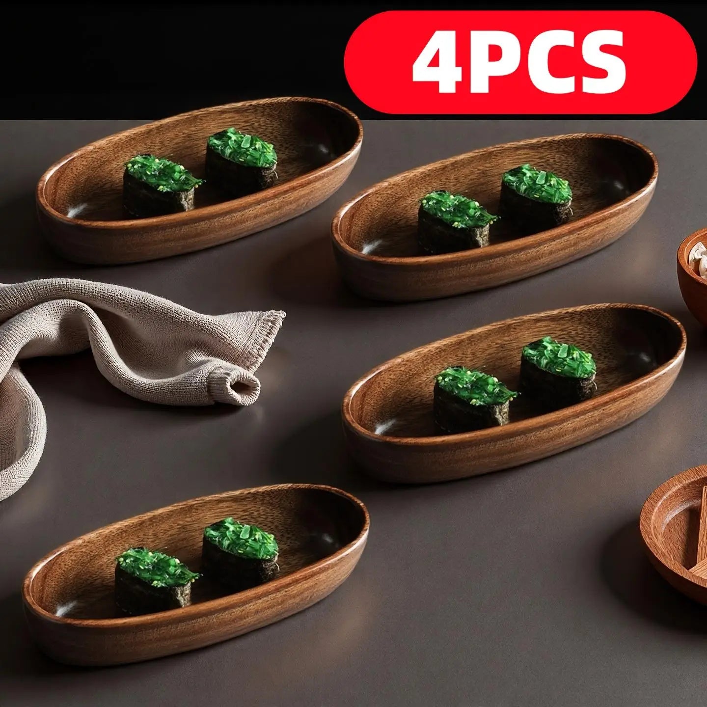 set de cuatro cuencos de servir de madera ovalados en un set de barco de madera artesanal para sushi japonés, cada uno con rollitos de sushi cubiertos con topping verde