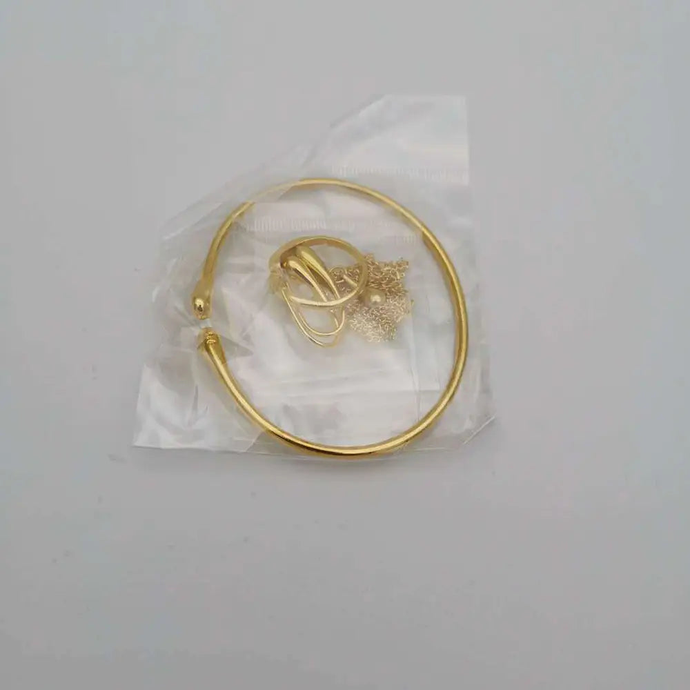Goldfarbiges offenes armreifarmband mit einer zarten kette und einem angehängten charm aus dem modernen silbernen tropfenförmigen schmuckset mit gemischten accessoires.