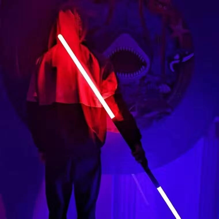 Sabre laser jouet 2-en-1 en métal rgb présentant un design allongé élégant, avec une lame rouge lumineuse et une poignée en métal noir.
