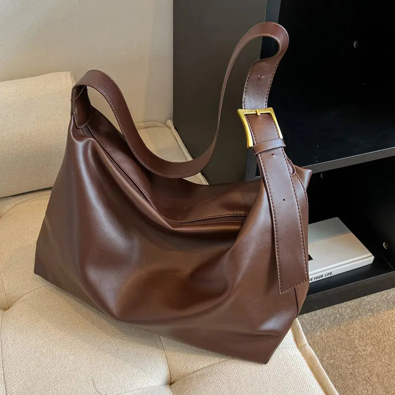 Brown leather hobo shoulder bag with gold-tone buckle and adjustable strap for versatile wear.