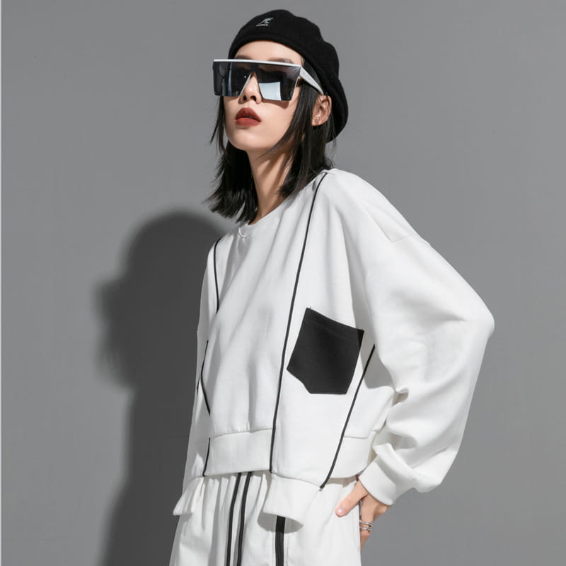 Haut à capuche oversize blanc pour femmes, avec surpiqûres contrastantes noires et une poche plaquée unique, pour des vêtements décontractés.