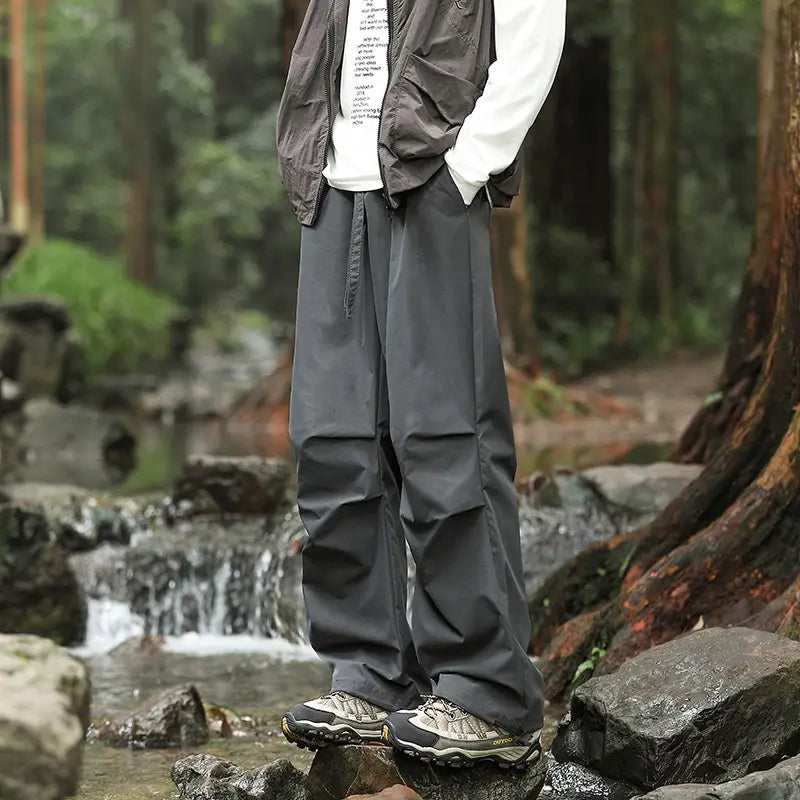Dark gray durable fabric pleated cargo hiking pants for men and women with a relaxed fit and visible side pockets.