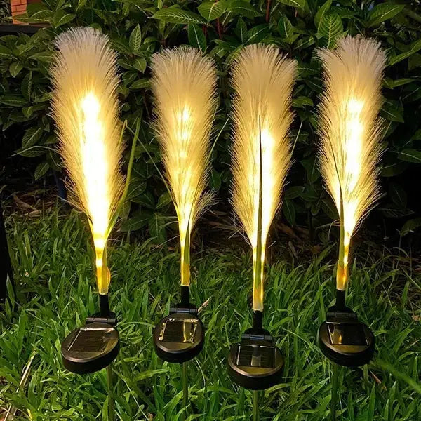 four golden feather-shaped solar garden lights with illuminated yellow tops and black waterproof base plates in a 4 pack set