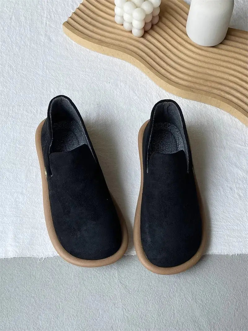 Schwarze Veloursleder-Slipper im Vintage-British-Stil mit niedrigem Absatz mit einer braun wirkenden Gummisohle.