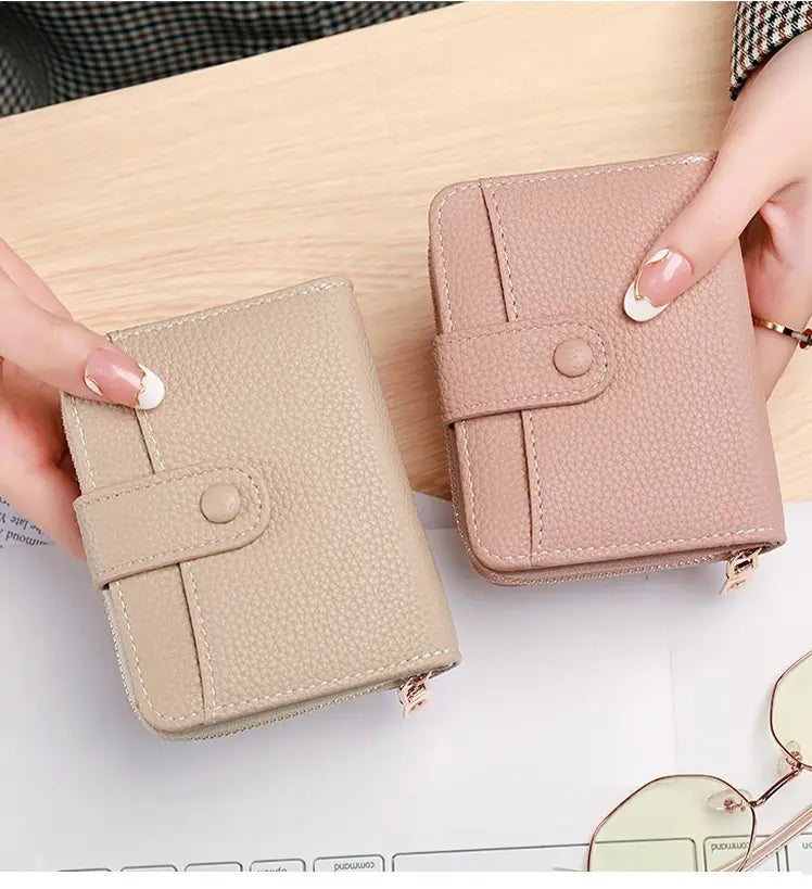 Leather mini organ wallets in beige and blush pink textured leather with button closures displayed side by side.