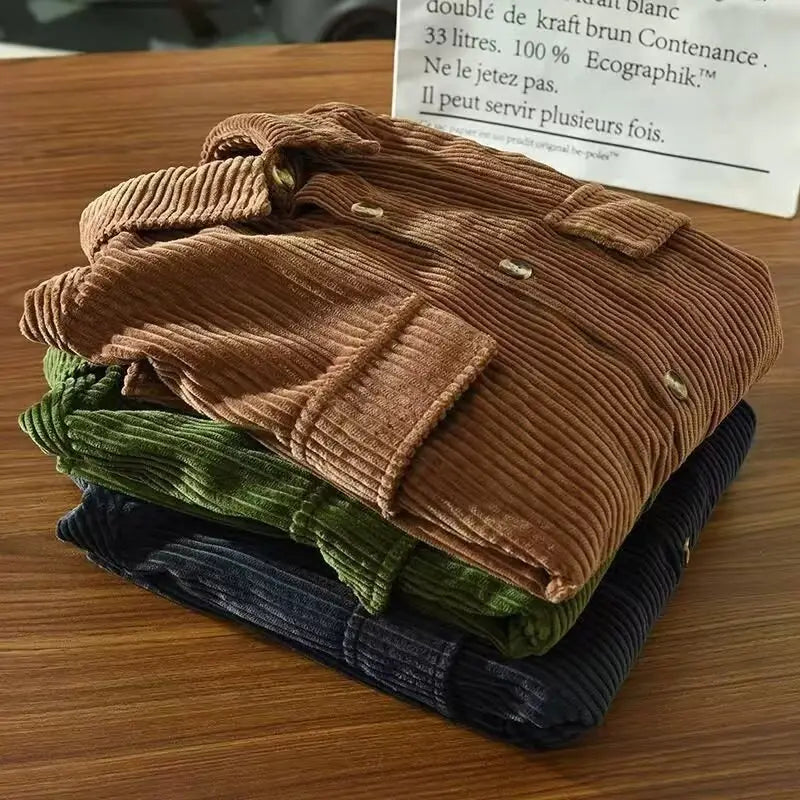Stapel von Herren-Cordhemden, schmal geschnitten, langarm, in erdigen Farbtönen aus Braun, Grün und Navyblau, geeignet für Herbstbekleidung.