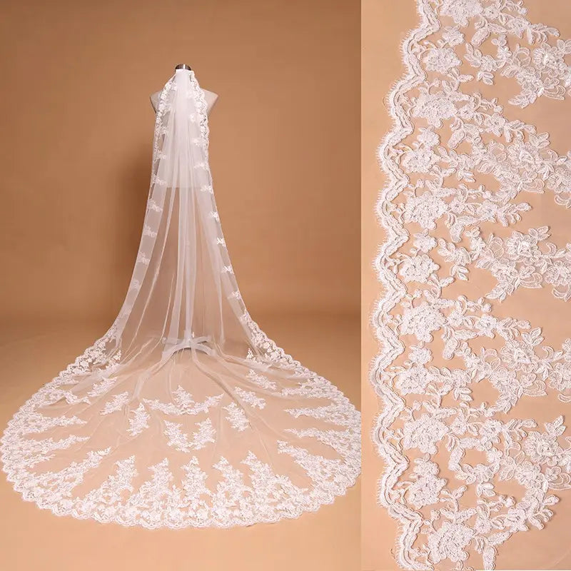 A delicate white embroidered floral lace cathedral wedding veil with comb featuring intricate floral embroidery and a scalloped edge displayed on a mannequin.