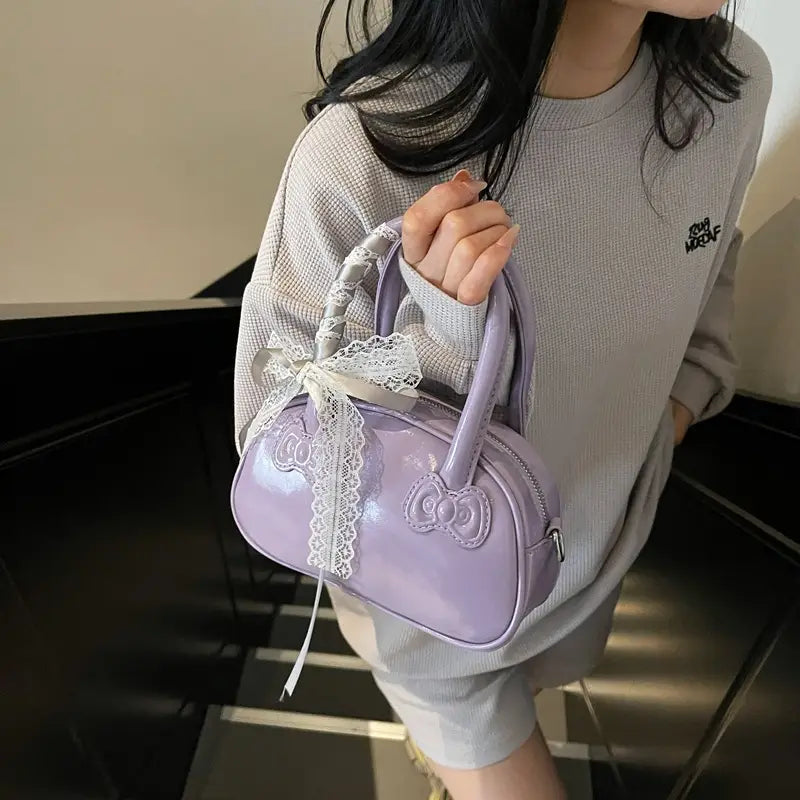 Lilac glossy hello kitty crossbody bag with lace trim and bow detailing.