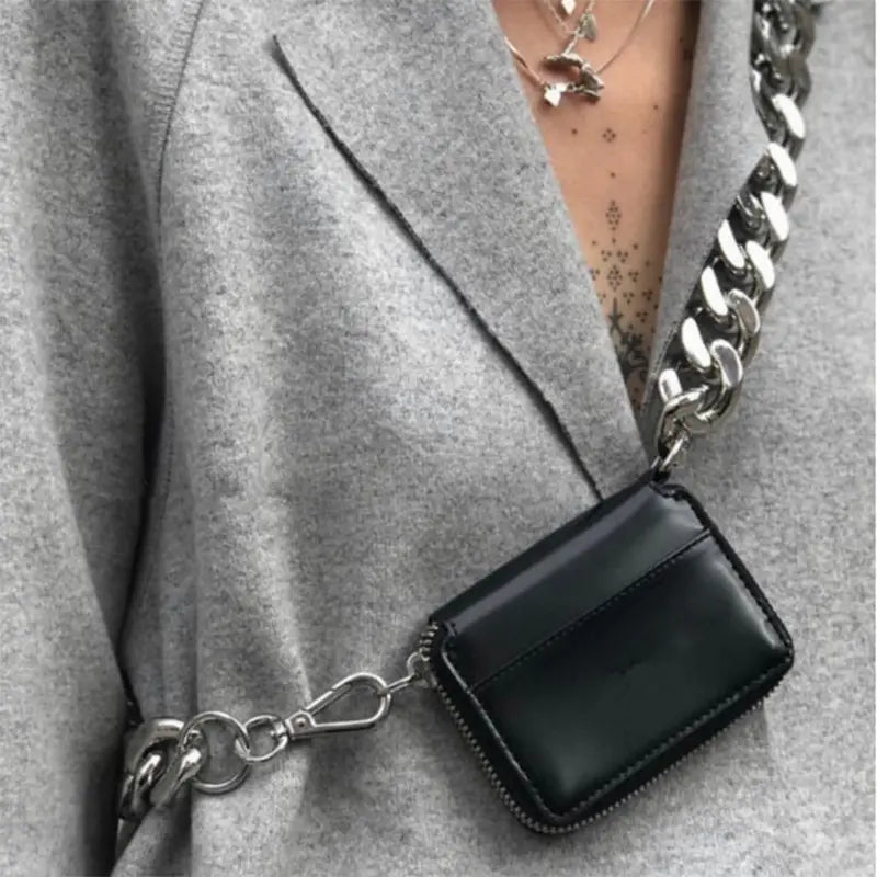 Black patent leather mini wallet with a chunky silver chain strap designed as a waist bag.