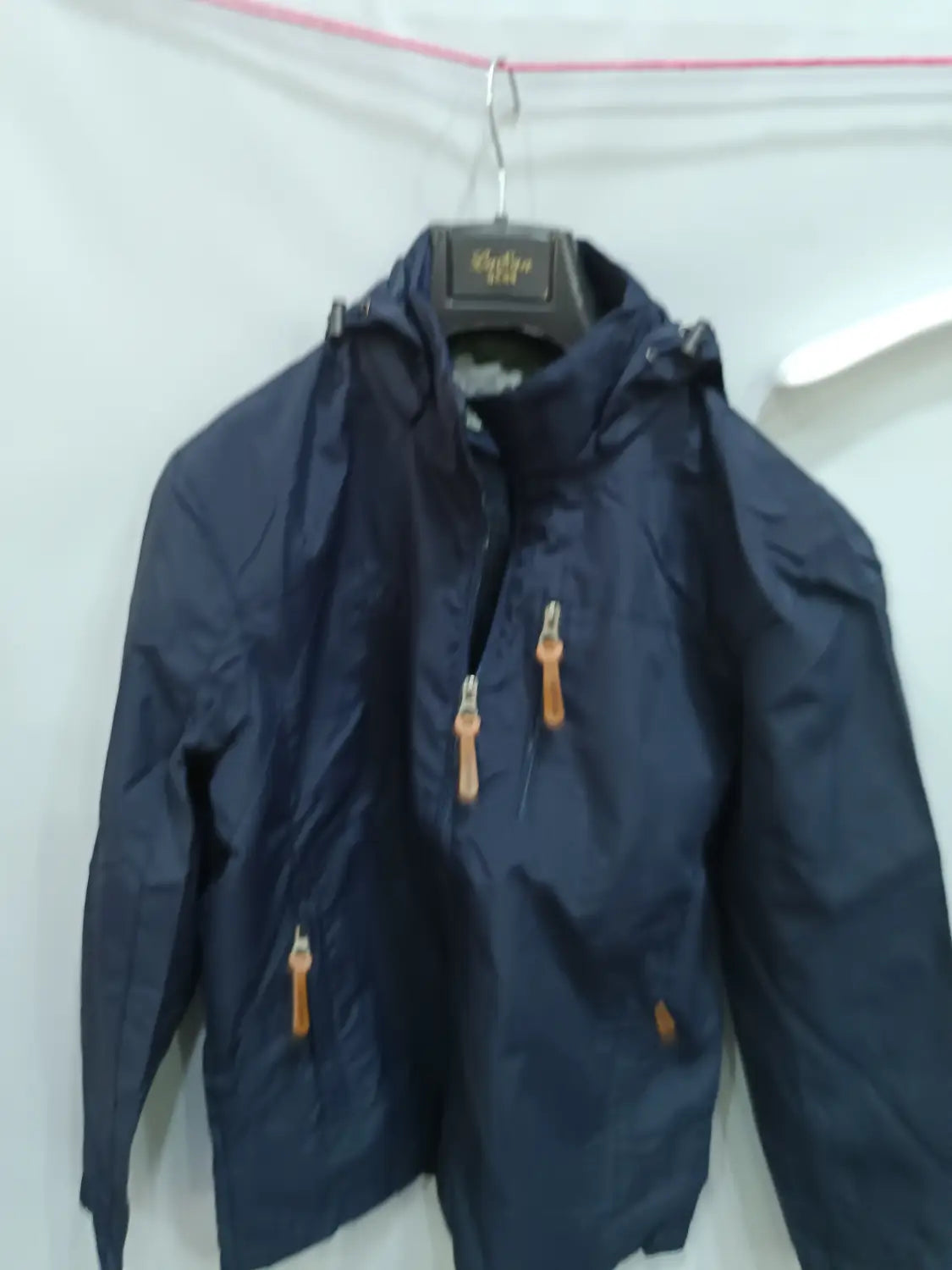 Chaqueta de senderismo con capucha impermeable color azul marino, con tiradores de cremallera color camel, diseñada para actividades al aire libre